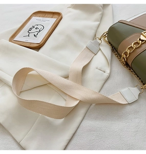 Detail of the woven strap and gold hardware on a two-tone green and beige bag