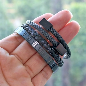 Close-up of three-piece black stainless steel men's bracelets with Roman numerals and braids