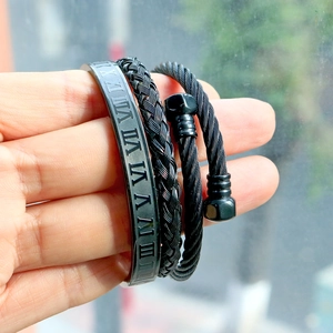 Detail of three-piece black stainless steel bracelet set with Roman numerals and woven cable