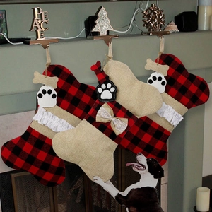 Three pet Christmas stockings with buffalo plaid and dog bone tags hanging on a fireplace