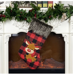 Classic red plaid Christmas stocking with faux fur cuff and reindeer hanging on fireplace