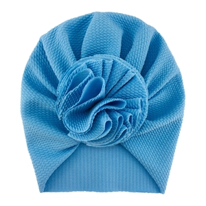 Detailed macro view of the blue baby turban hat with waffle texture and large fabric flower