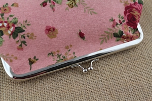 Close-up of vintage rose canvas fabric and silver kiss-lock metal clasp on a floral purse