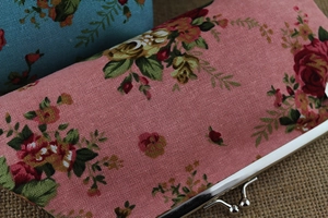 Close-up of floral canvas clutch bag with silver metal clasp and rose pattern print