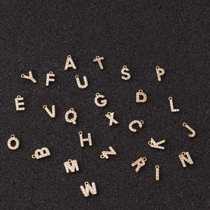 Gold letter charms with cubic zirconia stones for DIY jewelry making on black background