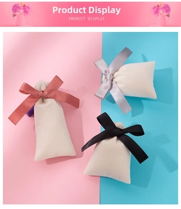 Detail view of small beige velvet jewelry pouches with decorative satin bow drawstrings