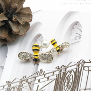 Detailed view of bee brooch with white pearl, rhinestone wings and enamel finish