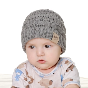 Close-up of grey knit baby beanie with leather MOK label and cute bear onesie detail