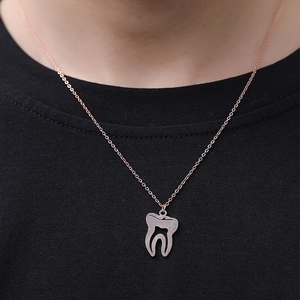 Gros plan du pendentif dent en argent avec chaîne or rose sur t-shirt noir