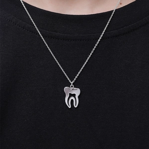 Vue detaillee d'un collier avec pendentif en forme de dent argentee sur un t-shirt noir