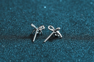 Macro shot of S925 sterling silver bow earrings on a blue glitter star background