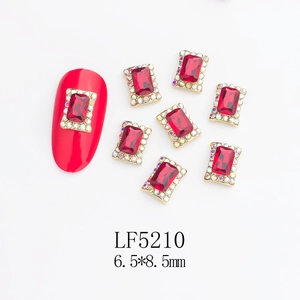 Macro detail of red 6.5x8.5mm K9 glass nail gems with rhinestone borders and alloy base