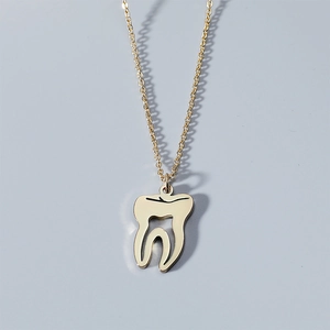 Vue détaillée du collier pendentif dent anatomique en or avec détails évidés polis