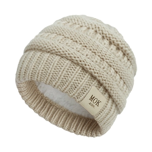 Close-up of beige cable knit baby hat featuring warm fleece lining and leather logo tag