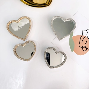 Detailed view of heart-shaped glitter mirror phone stands in gold and silver finish