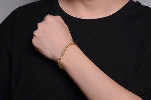 Close-up of a gold hip-hop Cuban link bracelet with rectangular clear crystals on a wrist