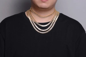 Close-up of a male model wearing multi-layered gold Cuban link chains with shimmering crystals