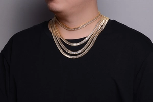 Detailed view of layered men's gold hip hop tennis chains with baguette-cut rhinestones