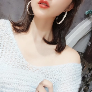 Close-up of oversized silver hoop earrings with shimmering rhinestones on a model