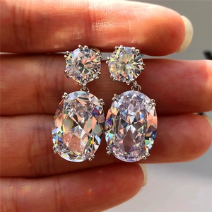 Macro shot of silver drop earrings with large oval zircon stones held between fingers