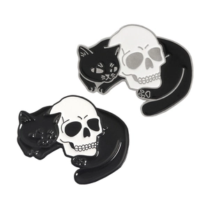 Close-up of cute gothic enamel pins featuring a black cat hugging a white skull detail