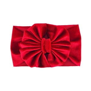 Macro shot of large red velvet bow on a stretchy wide headband for infants