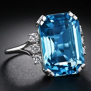 Elegante ring met smaragdgeslepen blauwe edelsteen en diamanten in witmetalen band