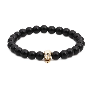 Black beaded elastic bracelet for men featuring a gold skull charm with zircon eyes