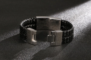 Detailed view of woven black leather men's bracelet with polished silver metal clasp
