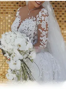 Détail d'une robe de mariée en dentelle blanche avec broderie florale et manches longues