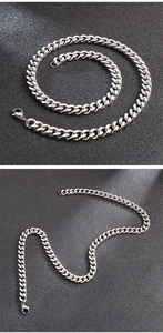 Detailed views of silver stainless steel Cuban link chain on a black textured surface
