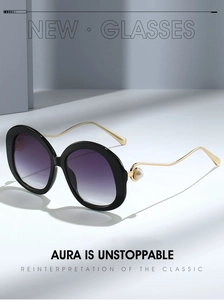 Detailed view of black oval sunglasses featuring golden wavy temples and pearl accents
