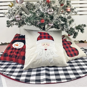 Close-up of Christmas pillow covers with Santa and reindeer motifs under a decorated tree