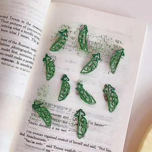 Trombones en métal vert en forme de cosse de pois sur une page de livre en anglais