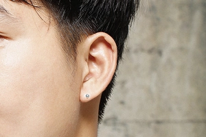 Gros plan d'une boucle d'oreille boule argentée avec fermoir à vis sur le lobe
