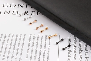 Boucles d'oreilles haltères en argent, or, or rose et noir sur un fond texturé élégant
