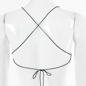 Détail d'un haut noir avec bretelles croisées et fermeture à lacets sur un mannequin blanc