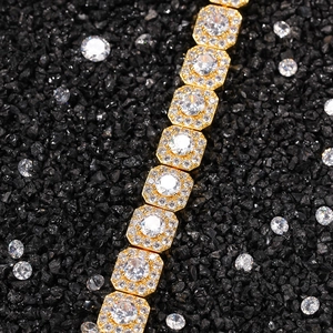 Macro shot of gold hip hop bracelet featuring square cubic zirconia links on dark stones