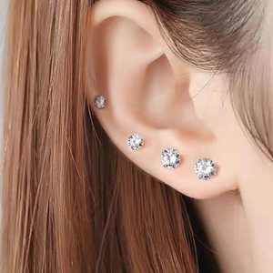 Macro view of four different sizes of silver cubic zirconia stud earrings on ear
