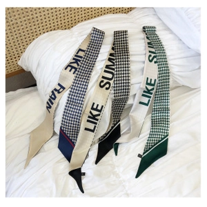 Trois foulards en soie avec motifs pied-de-poule et lettres imprimées sur literie blanche