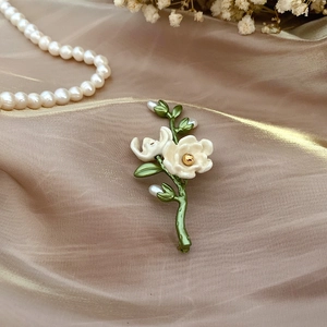 Vintage enamel camellia flower brooch with freshwater pearls on elegant silk background