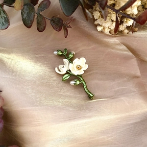Vintage enamel camellia flower brooch with freshwater pearls on silk background