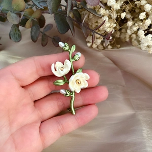 Detail of vintage magnolia brooch with ivory enamel petals and freshwater pearls