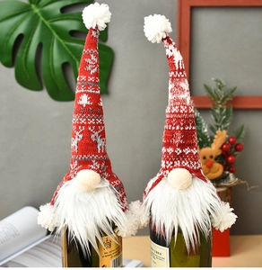 Close-up of a red knitted Christmas wine bottle cover with snowflake and reindeer patterns