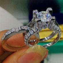 Close-up of a silver-toned double ring set featuring a green zircon center stone and pavé accents