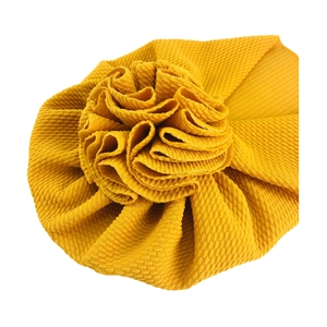Detailed view of mustard yellow waffle knit baby turban hat with decorative flower knot