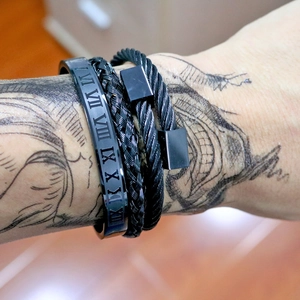 Detail of three-piece black jewelry set with roman numeral cuff and braided cord bracelets
