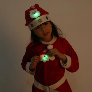 Luminous Santa face decoration glowing on a red plush Christmas dress and hat set