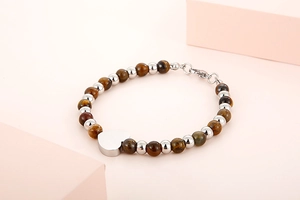Detail of tiger eye bead bracelet with silver heart pendant on decorative props