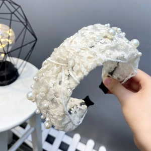 Detail of white lace headband with daisy embroidery and scattered faux pearl accents
